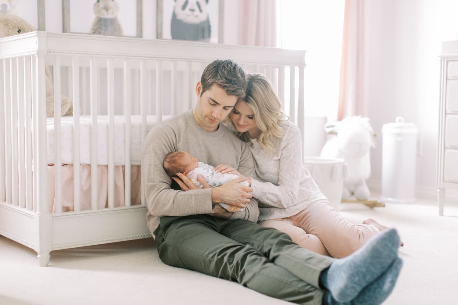 parent with their newborn baby sitting on the nursery floor